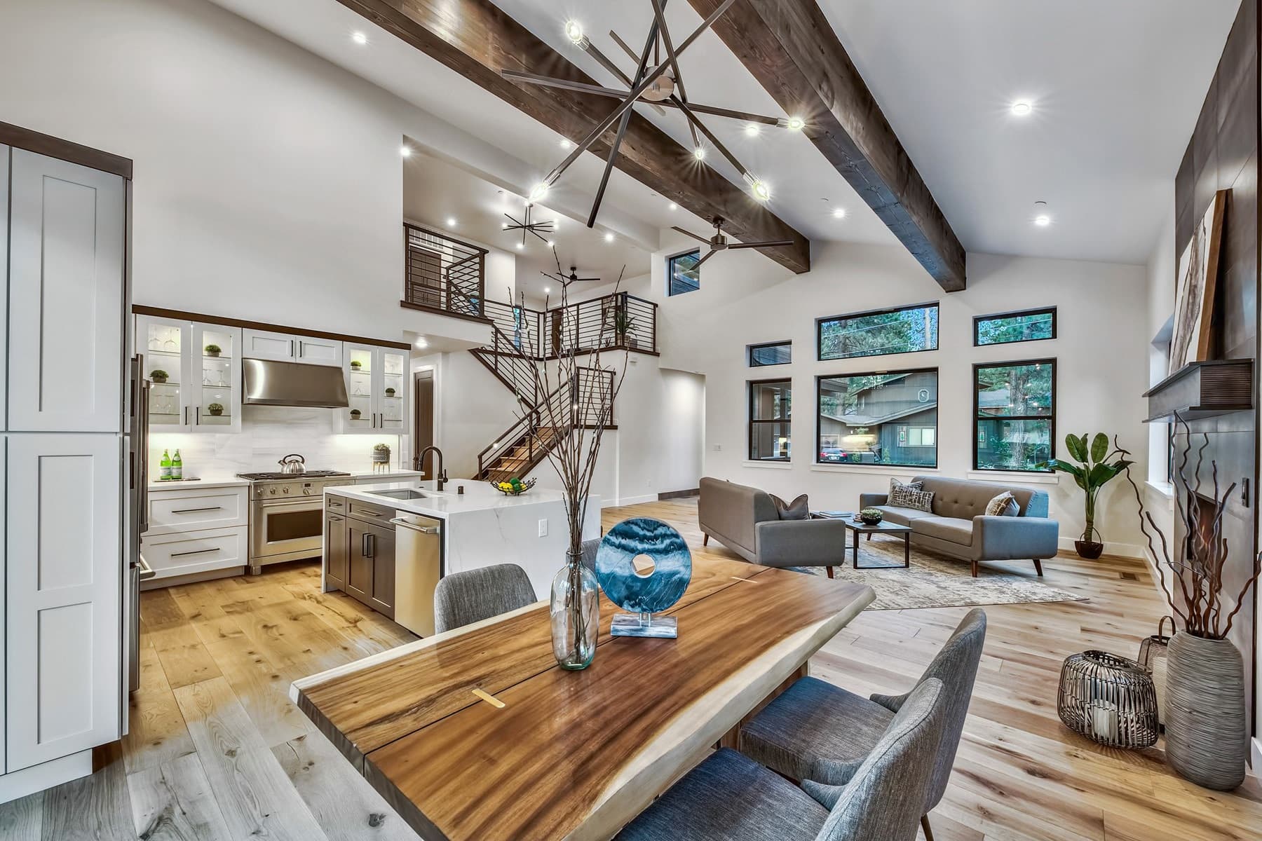 Open-plan great room and kitchen with a vaulted beamed ceiling and a live-edge dining table.